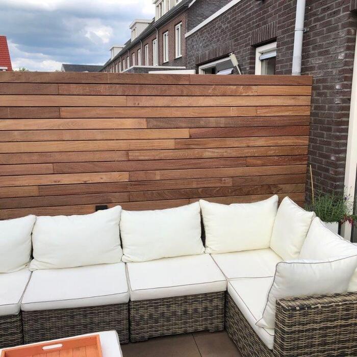 Renewing an old fence by screwing new Ipe timber slats onto the existing structure for a modern refit.